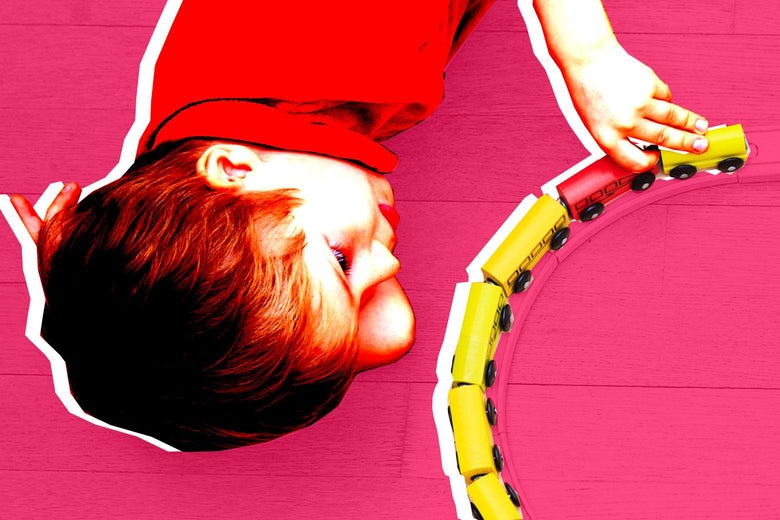 A boy playing with a wooden train.